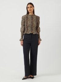 Blouse à imprimé léopard avec un col et des manches ruffle, associée à un pantalon large noir. Tissu lisse, éclat subtil et coupe élégante.