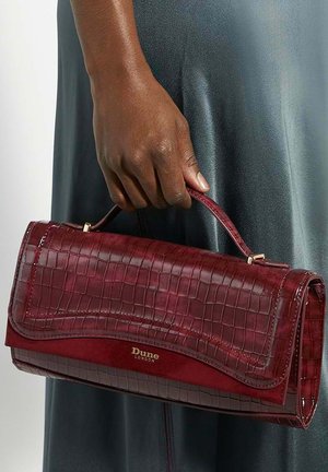 Burgundy handbag with a crocodile skin texture, slim shape, and subtle gold hardware. Features a flap closure and a short handle.