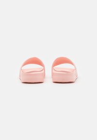 Sandali rosa slip-on con una texture liscia e lucida e retro aperto. Le cinghie curve e la suola piatta offrono un design minimalista.