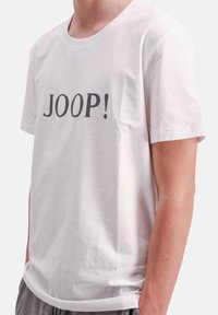 Witte katoenen t-shirt met een gedurfde zwarte "JOOP!" print op de voorkant, korte mouwen en een ronde halslijn. Zachte textuur, standaard pasvorm.