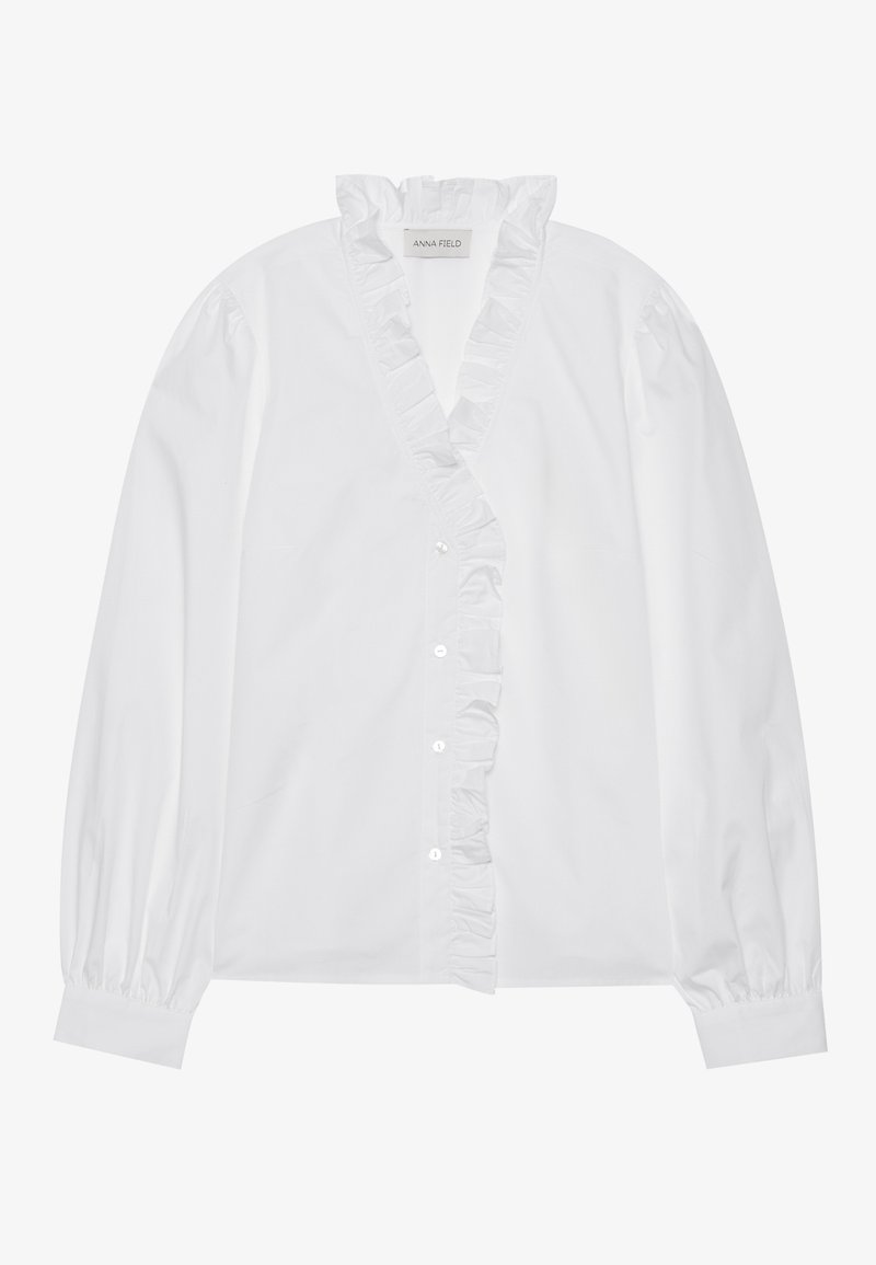 Chemise blanche à manches longues avec un col en V froncé. Dotée d'une fermeture à boutons et de poignets froncés, fabriquée en tissu lisse.