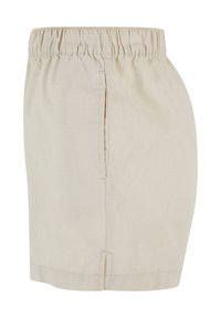 Short beige longueur genoux avec une taille élastique et des poches latérales, en tissu léger.