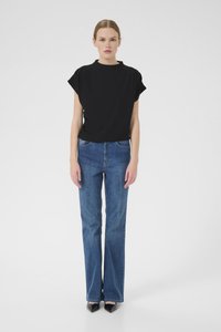 Top noir à manches courtes associé à un jean bleu évasé, avec un design classique à cinq poches et des talons noirs, sur un fond uni.
