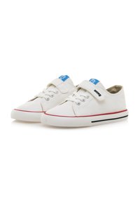 Zapatillas de lona blancas con una etiqueta azul en la lengüeta, detalles rojos en la suela y un cierre de tiras autoadhesivas para ponérselas fácilmente.