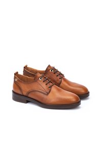 Chaussures habillées en cuir marron avec une finition lisse, bout rond, design à lacets et couture décorative. Elles possèdent un talon bas et des accents circulaires.