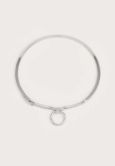 Choker din metal argintiu cu un finisaj neted și lustruit. Dispune de un inel circular central și un design minimalist, elegant.