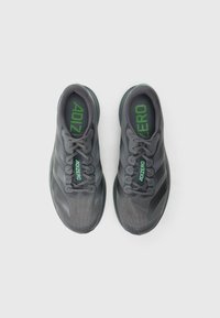 Chaussures de sport grises en tissu texturé, accents noirs et logo "ADIZERO" vert. Dotées d'un design lacé et d'une semelle rembourrée.