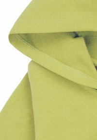 Jasnozielona tkanina złożona tak, aby pokazać fakturę i podwójnie przeszyty szew wzdłuż krawędzi.