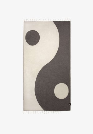 Rektangulært tæppe med stort yin-yang-design i sort og hvid, med frynser på de kortere kanter.