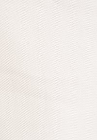 Tessuto di un beige chiaro con una sottile trama diagonale, caratterizzato da una leggera costolatura. La superficie è liscia e uniforme, con una leggera lucentezza.
