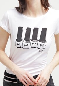 Bílý bavlněný tričko s grafikou čtyř flakonů s lakem na nehty, s etiketami "láska," "pot," srdce a "růžová," na jednobarevném pozadí.