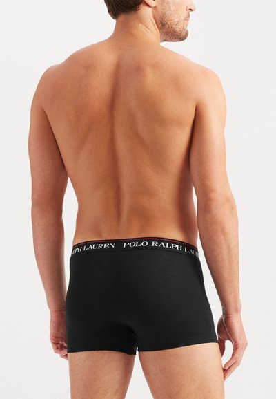 Boxeri scurți din bumbac negru, cu un brâu logo contrastant, prezentând o potrivire strânsă și o textură netedă. Vedere din spate care arată designul brâului.