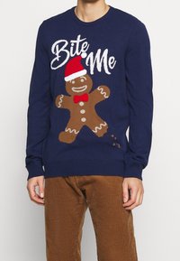 Granatowy sweter dzianinowy z grafiką piernikowego ludzika w czerwonym kapeluszu Mikołaja, białym napisem "Bite Me" oraz ściągaczami na mankietach i dole.