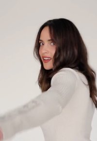 Hvit stripe strikkegenser med lange ermer, med skulderdetaljer. Modell poserer med håret løst og en naturlig sminkelook.