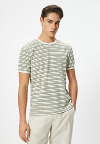 Stripet t-shirt i lysegrøn og hvid, lavet af blødt stof, med korte ærmer og rund halsudskæring. Diskret geometrisk mønster.
