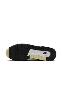 Suela de Nike Air con un diseño de goma texturizada en negro y crema, que presenta una entresuela blanca y un patrón de banda de rodadura prominente para tracción.