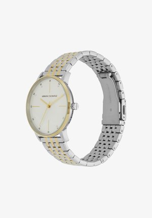 Hõbedane ja kuldne roostevabast terasest kell ümmarguse valge äratusega, minimalistlike markeritega ja kahetooni metallist linkpaelaga. Omab nupuvajutusega klambrit.