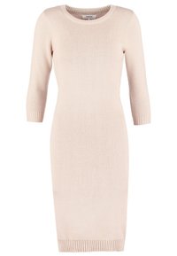 Robe en maille côtelée rose clair avec manches trois-quarts et encolure ronde, présentant une silhouette ajustée et des finitions côtelées à l'ourlet.