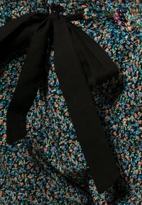 Bloemenpatroon stof in blauw, groen en oranje met een zwarte strik en knoopdetail op de taille, wat een textuurlijk uiterlijk biedt.