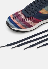 Scarpa sportiva multicolore con tomaia in mesh che presenta strisce orizzontali blu, rosa, arancione e viola. Include lacci blu scuro.