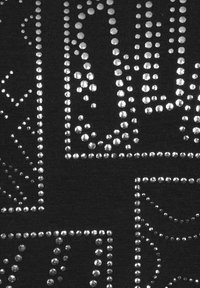 Zwarte stof met zilveren studs gerangschikt in geometrische patronen. Opvallende texturen creëren een treffend visueel contrast.