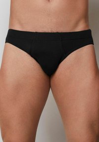 Svarta bomullsboxershorts med en tajt passform, med platta sömmar och en låg midjeresår. Slät yta utan synliga mönster eller dekorationer.