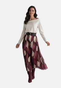 Biały top odsłaniający ramiona zestawiony z plisowaną spódnicą w bordowym kolorze z dużymi kremowymi i ciemnymi okręgami, podkreślony czarnym paskiem i kozakami za kolano.