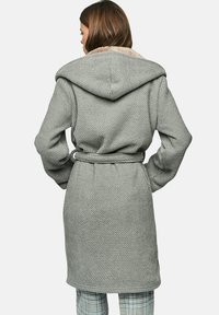 Grijze geweven robe met een capuchon en riem, voorzien van een textuurstof en zachte voering. De achterkant toont een relaxte pasvorm en minimale ontwerpdetails.