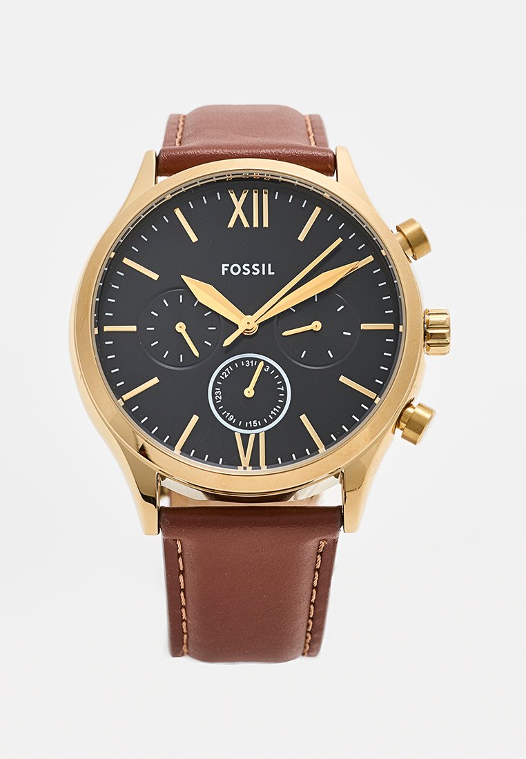 Reloj de tono dorado con esfera negra, correa de cuero marrón, marcadores en números romanos y tres subesferas para funcionalidades adicionales de cronometraje.