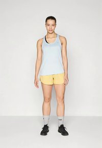 Camiseta de tirantes azul claro, pantalones cortos amarillos, calcetines grises y zapatillas negras. Tela suave, ajuste atlético y diseño sencillo. Sin patrones ni detalles adicionales.