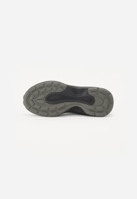 Semelle de chaussure de sport en caoutchouc noir avec motif de traction texturé gris ; présente un design contouré et des segments flexibles et rembourrés pour le confort.