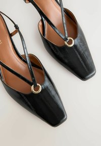 Mustad slingback kingad ruudukujulise varbaga, tekstureeritud nahast pealsega, ristitud rihmade ja kuldse rõngakujulise detailiga. Sile sisemine vooder beežis toonis.