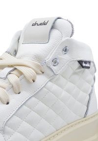 Sneaker bianco in pelle con texture trapuntata, lacci crema e accenti grigio. Presenta il logo sulla linguetta e dettagli in metallo sugli occhielli.