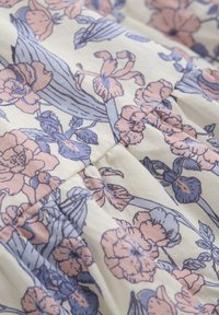 Blommig tyg med en krämfärgad bakgrund och rosa och blå blommor, med en strukturerad bomullsmaterial och detaljerade botaniska designelement.