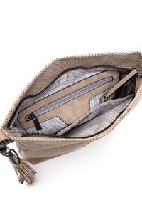 Beżowa torebka z perforacją i otwartym zamkiem, ukazująca wnętrze z zamkniętą kieszonką, podszewką z drukowanej tkaniny oraz przyczepioną breloczką z frędzlami.