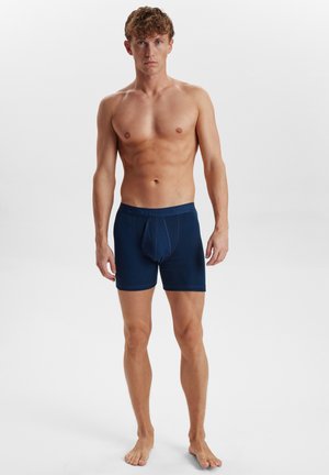 Mørkeblå boxer shorts med en tætsiddende pasform, lavet af blødt materiale, der har en kontrastfarvet linning med logo og en understøttende frontlomme.