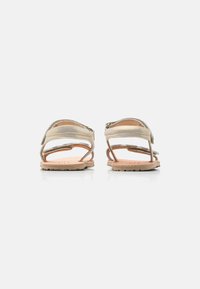 Tan läder sandaler med en texturerad beige remdesign, öppen baksida och gummisålar, med minimalistisk stil och inga utsmyckningar.