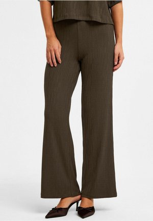 Pantalons larges texturés marron avec un subtil motif de rayures verticales. Associés à des mules noires à talons avec des accents en forme de nœud.