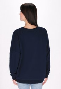 Námořnický oversized svetřík s dlouhými rukávy, kulatým výstřihem a pružnými manžetami. Měkká tkanina s hladkou strukturou a minimálními švy.