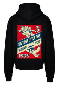 Svart hettegenser med et fargerikt trykk på ryggen som viser tre griser og den store stygge ulven, med tekst som fremhever "1933."
