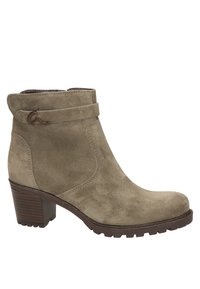Bottine en daim verte olive avec un design incurvé, une sangle latérale accentuée et un talon bloc pour plus de stabilité. Semelle texturée avec adhérence.