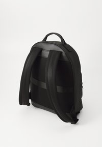 Schwarzer Rucksack mit einer glatten Lederoberseite, Netzrücken und gepolsterten Trägern. Verfügt über verstellbare Träger und einen Tragegriff oben.