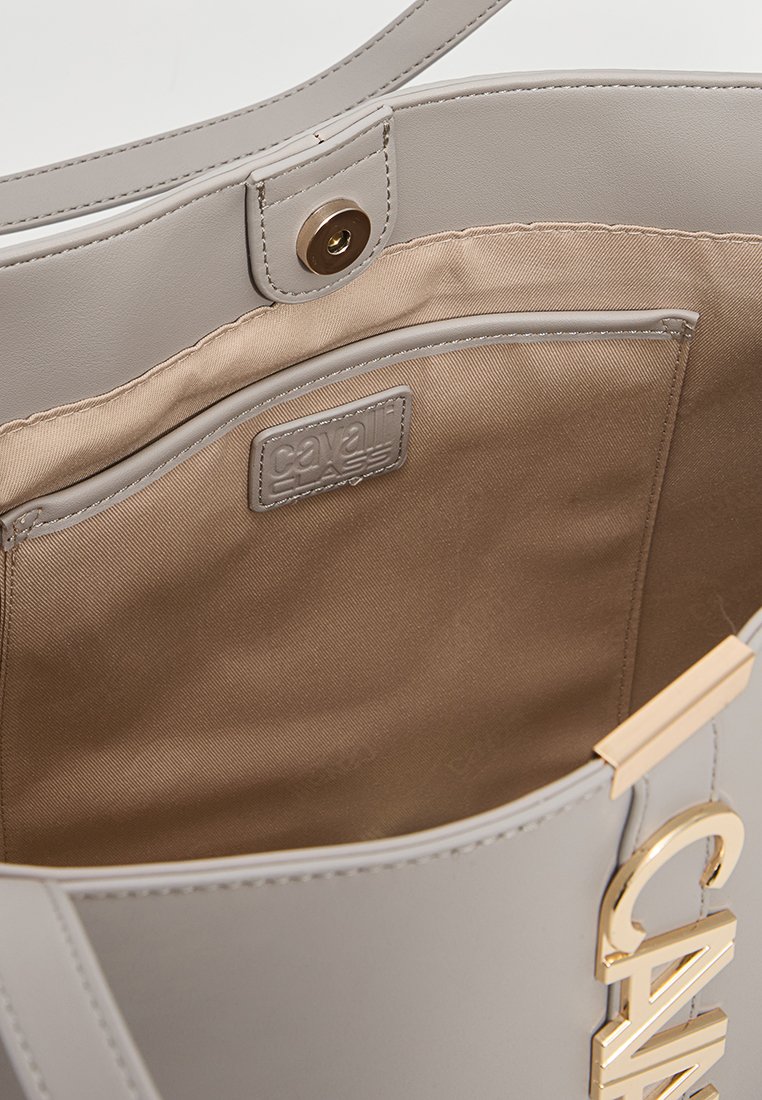 Hellgraue Tragetasche mit einer glatten Kunstleder-Oberfläche und goldenen Beschlägen. Innen mit beigem Stoff ausgekleidet, mit einer kleinen Tasche und Branding.