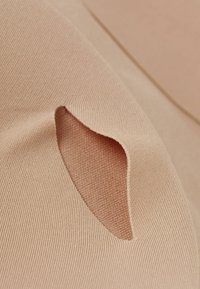 Béžová tkanina s texturovaným povrchem, která má malý, prodloužený výřez. Materiál je měkký a elastický.