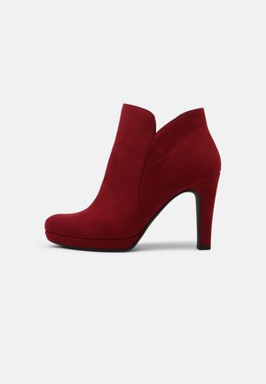 Røde ruskinds ankelstøvler med en slank, spids tå og en høj stilettohæl. Designet har et buet udsnit foran.