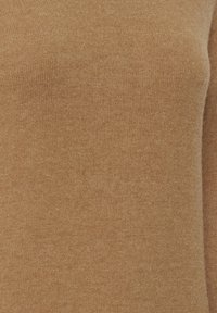 Tejido de punto de color marrón claro con una textura suave, que presenta un patrón sutil y una distribución de color uniforme.