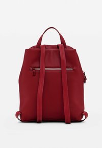 Mochila de cuero rojo con un diseño estructurado, que cuenta con dos correas para los hombros, asas superiores y un bolsillo frontal con cremallera. Textura suave.