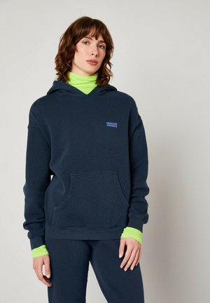 Mørkeblå hættetrøje med en frontlomme, ribbede manchetter og en grøn lagdelt turtle-neck under. Har et lille "American Vintage" logo.