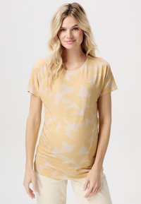 Korte mouw top van zachte gele stof, voorzien van een groot bloemenpatroon in een lichtere tint. Ronde halslijn en een relaxte pasvorm.