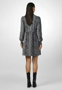 Harmaan leopardi-kuosiset mekko, jossa on pitkät puff-hihat, kerätty vyötärö ja polven mittainen helma. Yhdistetty mustien nilkkureiden kanssa.
